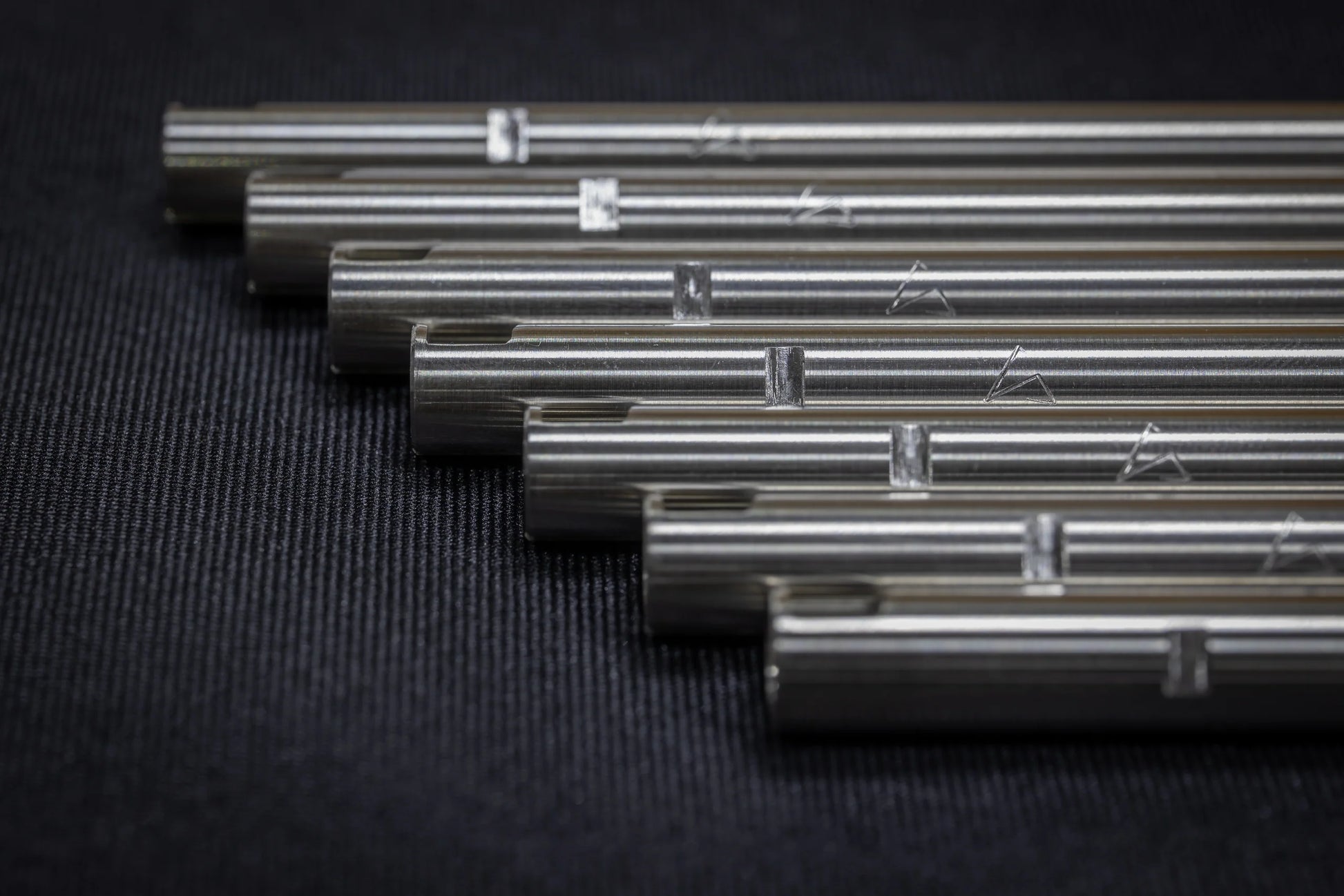 A row of stainless steel SPARK Hiei Kai 6.05mm tight bore inner barrels by AIRSOFT97 displaying their precision cut hop-up windows and laser-engraved alignment markings.